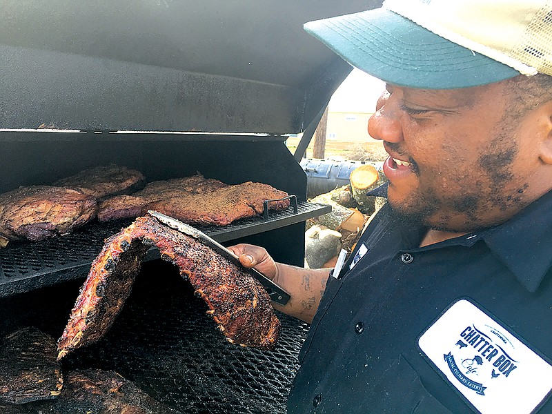 Chatter Box Cafe owner Brandon Ellis lifts a full rack of ribs off the grill inside his woodburning smoker on Market Street in Chattanooga. (Staff Photo by Matt McClane)