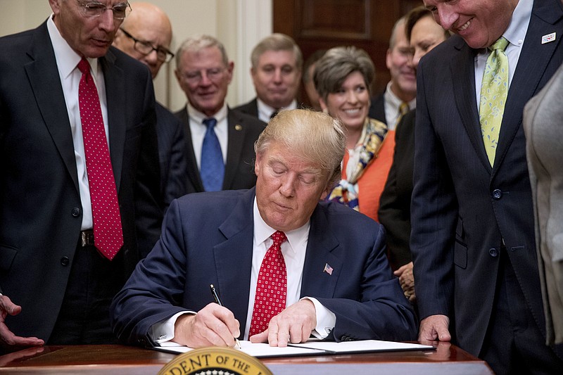 
              President Donald Trump signs the Waters of the United States (WOTUS) executive order, Tuesday, Feb. 28, 2017, in the Roosevelt Room in the White House in Washington, which directs the Environmental Protection Agency to withdraw the Waters of the United States (WOTUS) rule, which expands the number of waterways that are federally protected under the Clean Water Act. (AP Photo/Andrew Harnik)
            