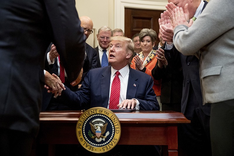 
              President Donald Trump shakes hands after signing the Waters of the United States (WOTUS) executive order, Tuesday, Feb. 28, 2017, in the Roosevelt Room in the White House in Washington, which directs the Environmental Protection Agency to withdraw the Waters of the United States (WOTUS) rule, which expands the number of waterways that are federally protected under the Clean Water Act. (AP Photo/Andrew Harnik)
            