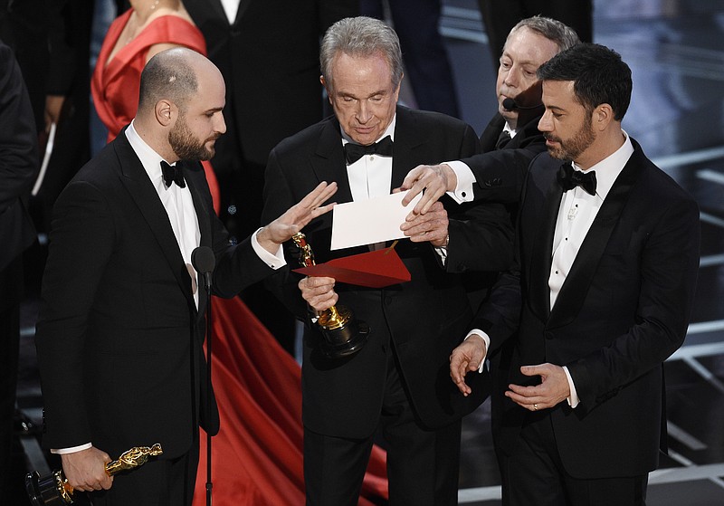
              "La La Land" producer Jordan Horowitz, left, presenter Warren Beatty, center, and host Jimmy Kimmel right, look at an envelope announcing "Moonlight" as best picture at the Oscars on Sunday, Feb. 26, 2017, at the Dolby Theatre in Los Angeles. It was originally announced mistakenly that "La La Land" was the winner. (Photo by Chris Pizzello/Invision/AP)
            