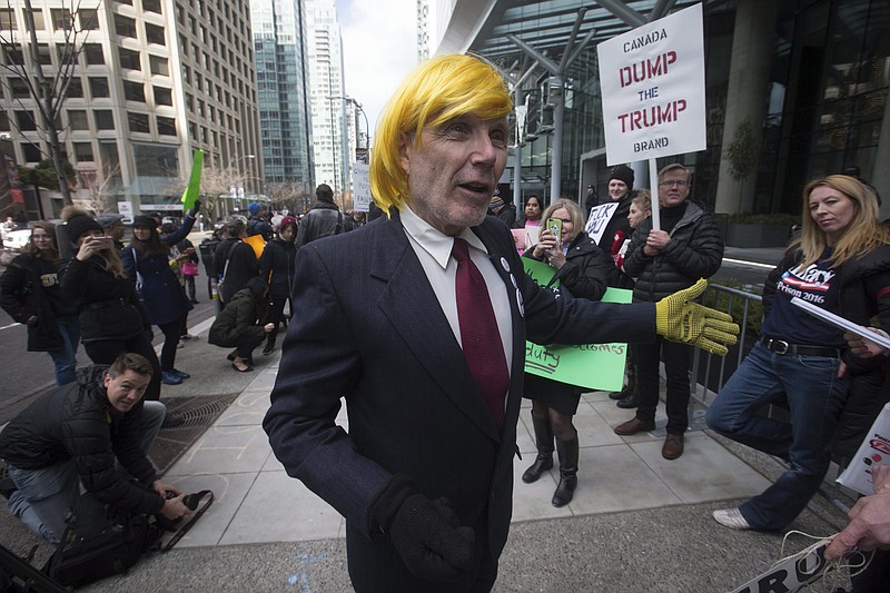 A man dressed as U.S. President Donald Trump stands among protesters outside the official opening of the Trump International Hotel and Tower in Vancouver, Canada, on Tuesday, Feb. 28, 2017. U.S. President Donald Trump's sons Donald Jr. and Eric attended the opening. (Darryl Dyck/The Canadian Press via AP)