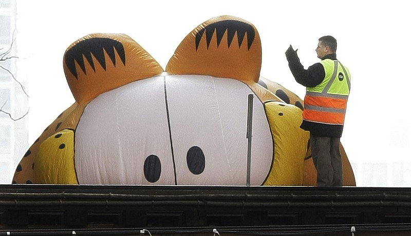 
              FILE - In this Nov. 27, 2008, file photo, the Garfield the Cat helium balloon appears to be peering at a Chicago Transit Authority worker on the elevated tracks inside Chicago's famed Loop during the Thanksgiving Day Parade in Chicago. Garfield creator Jim Davis sought to quell a controversy over the cat's gender by telling The Washington Post on Feb. 28, 2017, that the cat is male. (AP Photo/Charles Rex Arbogast, File)
            