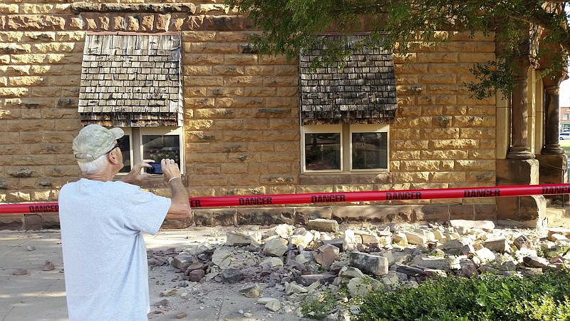 
              FILE - In this Saturday, Sept. 3, 2016 file photo, Steve Gibson, of Pawnee, takes photos of damage to a building in downtown Pawnee, Okla., following a 5.6 magnitude earthquake. An Oklahoma-based Native American tribe, the Pawnee Nation, filed a lawsuit in its own tribal court system accusing several oil companies in the state's largest earthquake that caused extensive damage to some near-century-old tribal buildings. (David Bitton/The News Press via AP, File)
            