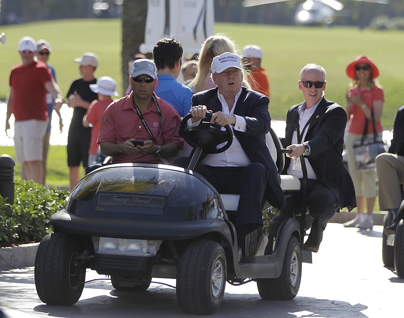 
              FILE- In this March 6, 2016 file photo, Donald Trump drives himself around the golf course to watch the final round of the Cadillac Championship golf tournament in Doral, Fla. President Donald Trump's executive order seeking to rewrite a rule that protects small streams from pollution raises new questions about financial conflicts of interest for a president whose business holdings include a dozen U.S. golf courses. It's not clear whether any financial benefits from more lax regulation of waterways on golf courses could violate laws meant to keep politicians from using public office for personal gain, but experts say it adds to an appearance of impropriety.(AP Photo/Luis Alvarez, File)
            