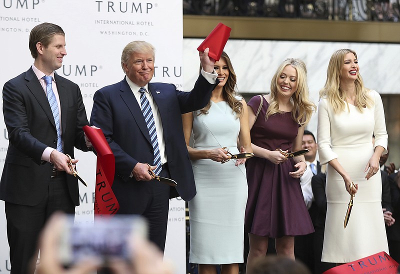 
              FILE - In this Oct. 26, 2016 file photo, then-Republican presidential candidate Donald Trump, together with his family, from left, Eric Trump, Melania Trump, Tiffany Trump and Ivanka Trump, waves part of a ribbon after cutting the ribbon during the grand opening of Trump International Hotel in Washington. Trump's $200 million hotel inside the federally owned Old Post Office building has become the place to see, be seen, drink, network, even live, for the still-emerging Trump set. It's a rich environment for lobbyists and anyone hoping to rub elbows with Trump-related politicos, despite the veil of ethics questions that hangs overhead.  (AP Photo/Manuel Balce Ceneta, File)
            