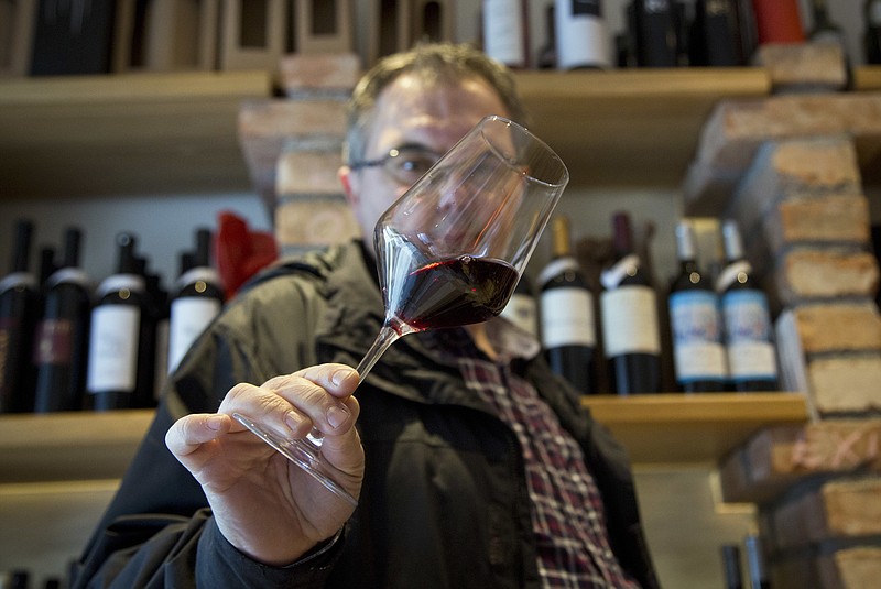 
              FILE - In this Wednesday, March 1, 2017 file photo, Robert Samek, a sommelier, inspects a glass of red wine at his wine shop in Zagreb, Croatia. Slovenian winemakers say they expect the European Commission to suspend the procedure of issuing a permit to Croatia to use the Teran red wine brand in the 28-nation bloc. The head of a Slovenian group to protect Teran, Marjan Colja, told The Associated Press on Friday, March 10 that his group has “no doubt” documentation presented by Croatia has been “partly forged.” (AP Photo/Darko Bandic, file)
            