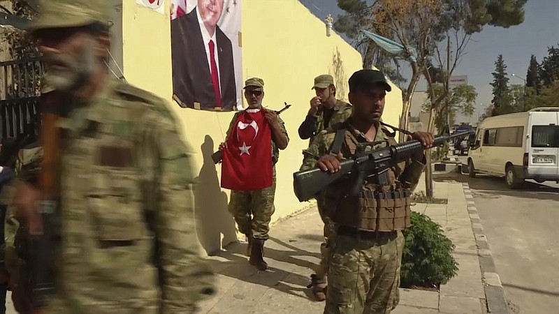 
              FILE - In this file image made from video posted online on Sunday, Oct. 16, 2016 by Qasioun News Agency, Turkish-backed Syrian opposition forces, one carrying a Turkish flag, patrol in Dabiq, Syria. Turkey’s military incursion in northern Syria succeeded in gaining it a foothold and driving Islamic State group militants away from its border _ but its determination to also push back the Kurds is causing it trouble. (Qasioun News Agency via AP, File)
            