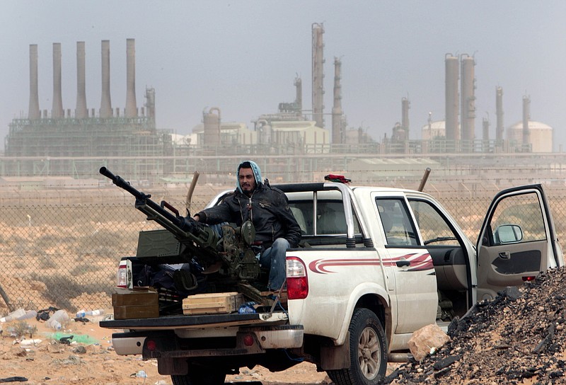 
              FILE - In this March 5, 2011 file photo, an anti-government rebel sits with an anti-aircraft weapon in front an oil refinery in Ras Lanouf, eastern Libya. The fight for Libya’s Ras Lanuf refinery and nearby Sidr depot threatens to spiral into open conflict between rival factions vying for power from east and west. With both sides claiming the facilities as their own but control unclear, decisive days lie ahead. (AP Photo/Hussein Malla, File)
            