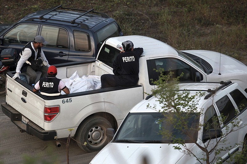 
              In this April 11, 2015 photo, special investigators guard bodies found in mass graves in a wooded area known as Colinas de Santa Fe on the outskirts of Veracruz, Mexico. Veracruz state's top prosecutor, Jorge Winckler, said the clandestine pits appeared to contain remains of cartel victims killed years ago. (AP Photo/Felix Marquez)
            