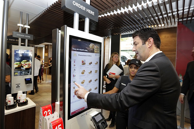
              FILE - In this Thursday, Nov. 17, 2016, file photo, McDonald's CEO Steve Easterbrook demonstrates an order kiosk, with cashier Esmirna DeLeon, during a presentation at a McDonald's restaurant in New York's Tribeca neighborhood. McDonald’s has started testing mobile order-and-pay after acknowledging the ordering process in its restaurants can be “stressful.” The company is testing the option in California and Washington ahead of a national launch in the U.S. toward the end of 2017. Easterbrook has noted the initial stages of visiting can be “stressful” and that the company is making changes to improve the overall customer experience. That includes the introduction of ordering kiosks, which executives say can help ease lines at the counter and improve order accuracy. (AP Photo/Richard Drew, File)
            