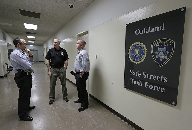 
              In this Friday, March 10, 2017, photo, from left Russell Nimmo, FBI supervisory special agent, and FBI agent Paul Healy talk with Oakland police detective Brad Baker outside the offices of the Oakland Safe Streets Task Force in Oakland, Calif. The federal government already plays a big role in fighting violent crime in cities, through grants and partnerships. Ten FBI agents now share an office with Oakland detectives, offering help gathering evidence, collecting DNA, chasing leads and bringing federal prosecutions that carry longer sentences in far-away prisons. (AP Photo/Eric Risberg)
            