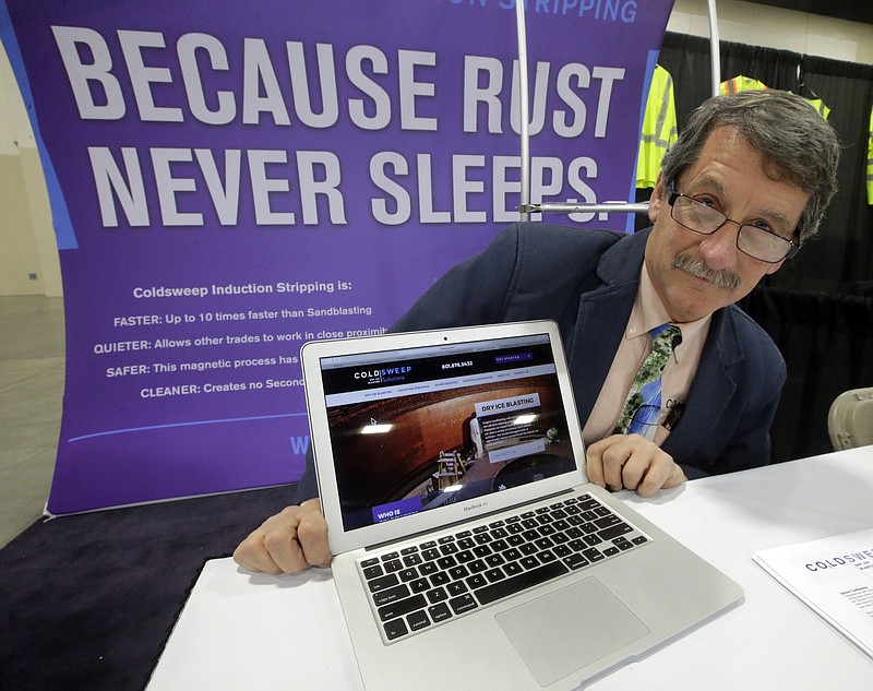 In this Tuesday, Feb. 28, 2017, photo, Randell Heath poses next to a laptop displaying his company's website, in Sandy, Utah. Heath's sandblasting company, near Salt Lake City, had its website hacked and turned into a store selling Viagra and Cialis. (AP Photo/Rick Bowmer)