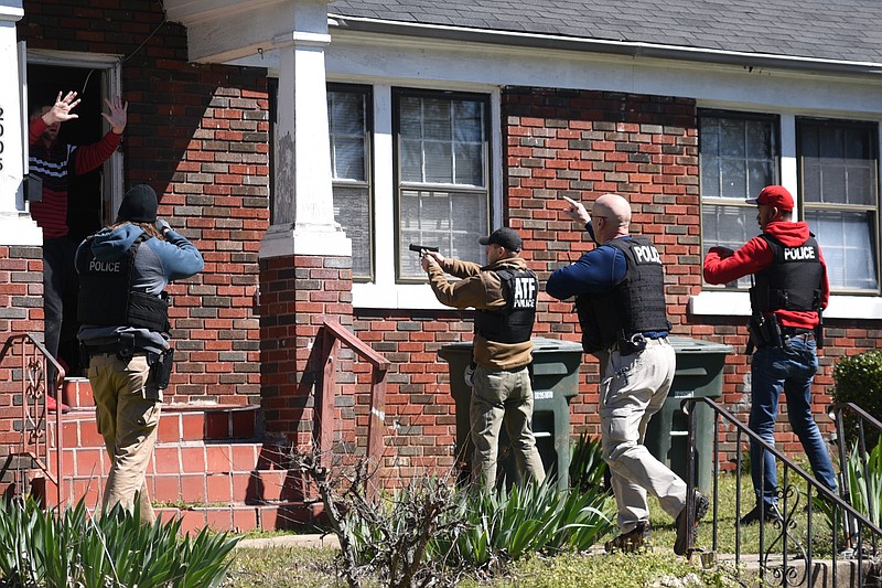 Officers from various agencies surround a door Wednesday, March 15, 2017 on Bennett Avenue in Chattanooga, Tenn., during a roundup to pick up people with outstanding warrants. 
