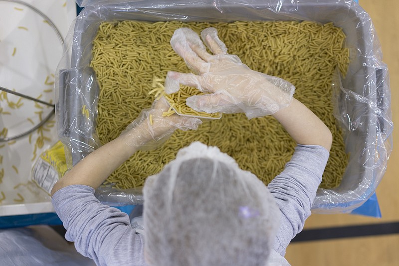 Lilly Glenister, 8, and other volunteers pack macaroni and cheese meals at Rivermont Presbyterian Church for the Chattanooga Area Food Bank.