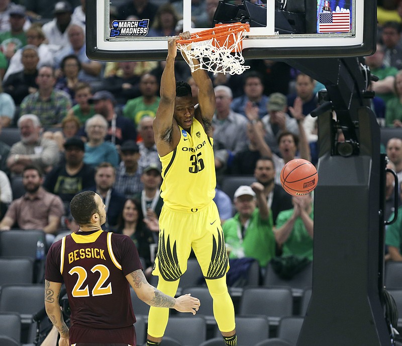 
              Oregon forward Kavell Bigby-Williams hangs on the rim after dunking as Iona forward Taylor Bessick, left, looks on during the first half of a first-round game in the men's NCAA college basketball tournament in Sacramento, Calif., Friday, March 17, 2017. (AP Photo/Steve Yeater)
            