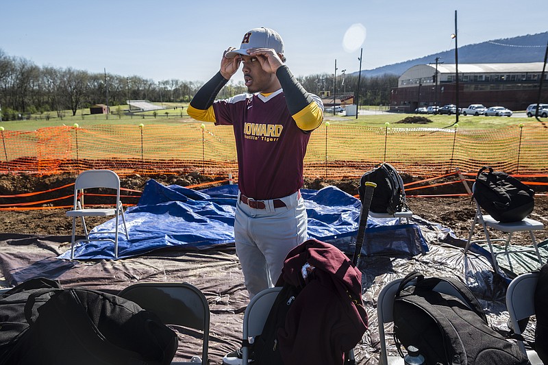 Howard player #7 puts on his hat in the makeshift dugout before Howard's first home baseball game in years at Howard High School on Wednesday, March 15, 2017, in Chattanooga, Tenn. The community rallied to donate materials, and the team and volunteers worked to restore the field for the school's baseball program.