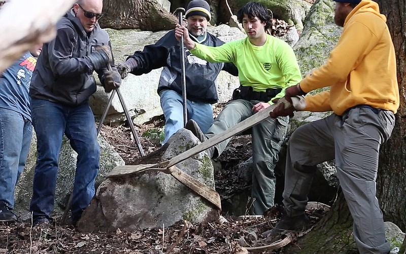 Volunteers assist Ranger Park Greer, second from right, in excavating a large rock for use in a new rock staircase along the Fiery Gizzard reroute.

