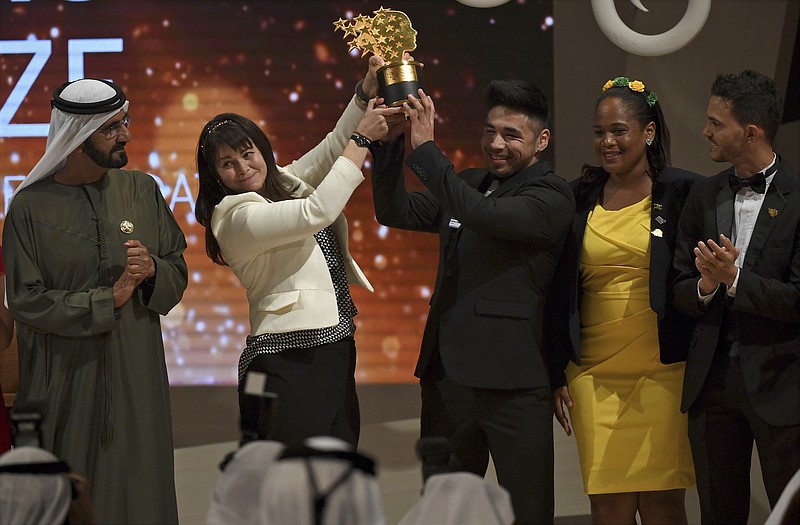 
              Canadian school teacher Maggie MacDonnell raises the Global Teacher Prize with one of her students while standing next to Dubai ruler Sheikh Mohammed bin Rashid Al Maktoum, in Dubai, United Arab Emirates, Sunday, March 19, 2017. MacDonnell whose teaching philosophy underscores hope and acts of kindness in an isolated corner of Quebec won a $1 million prize in what has become one of the most-coveted and high-profile awards for teaching excellence. MacDonnell beat out thousands of applicants from around the world. (AP Photo/Martin Dokoupil)
            