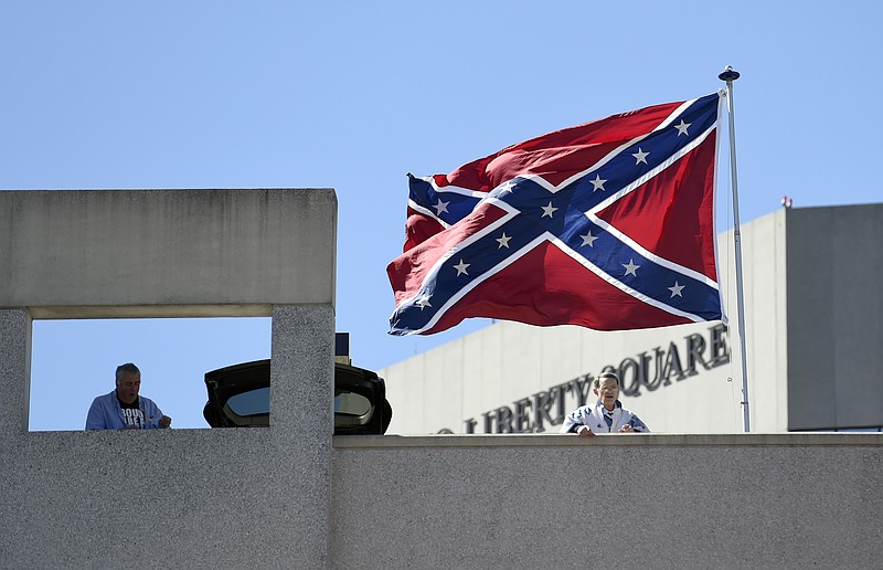 
              Basketball fans look out as a Confederate flag flies from a parking deck outside the arena before a second-round game of the NCAA men's college basketball tournament in Greenville, S.C., Sunday, March 19, 2017. A small group of protesters flew a large Confederate flag from the top of a parking garage next to the arena hosting two men's NCAA Tournament games. (AP Photo/Rainier Ehrhardt)
            