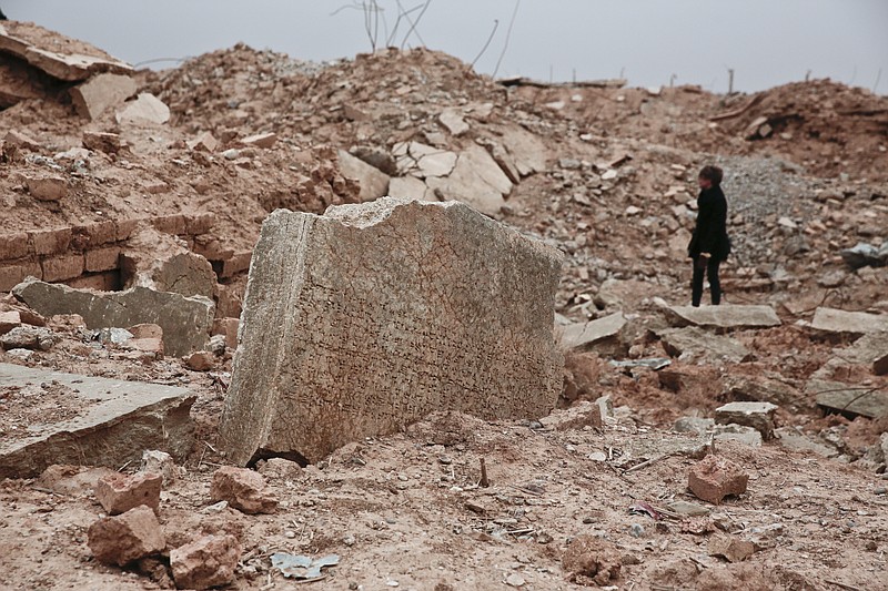 
              FILE - In this Wednesday, Dec. 14, 2016 file photo, a stone tablet with cuneiform writing in the foreground as UNESCO's Iraq representative Louise Haxthausen documents the damage wreaked by the Islamic State group at the ancient site of Nimrud, Iraq. France is trying to raise tens of millions of dollars from international donors who gathered Monday March 20, 2017, to protect cultural heritage sites threatened by war and the kind of destruction carried out by Islamic State militants. (AP Photo/Maya Alleruzzo, File)
            