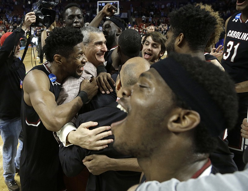 
              South Carolina head coach Frank Martin, second from left, is hugged by Chris Silva, left, as they celebrate after a second-round game against Duke in the NCAA men's college basketball tournament in Greenville, S.C., Sunday, March 19, 2017. (AP Photo/Chuck Burton)
            