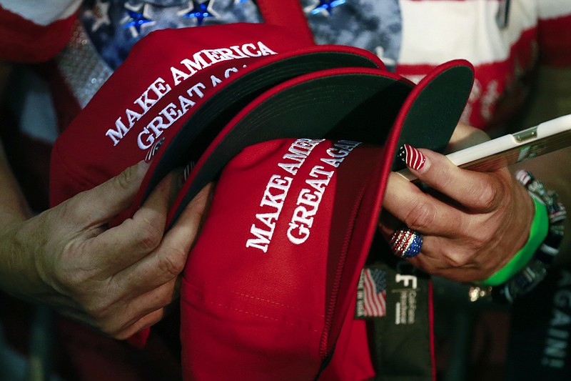 In this June 2, 2016, file photo, a woman holds hats to get them autographed by Republican presidential candidate Donald Trump during a rally in San Jose, Calif. The New York Post reported on March 19, 2017, that a Philadelphia man sued a New York City bar, claiming he was denied service for wearing such a hat. (AP Photo/Jae C. Hong, File)