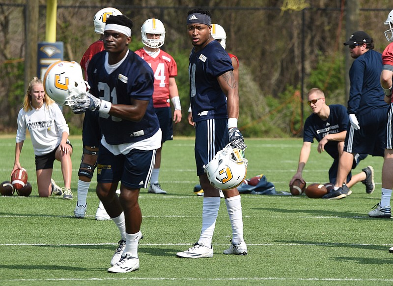 Tae Davis, right, (19) watches as K.J. Roper (31) prepares to put on his helmet during spring practice Tuesday at Scrappy Moore Field. Davis is beginning his switch from safety to linebacker for the 2017 season.