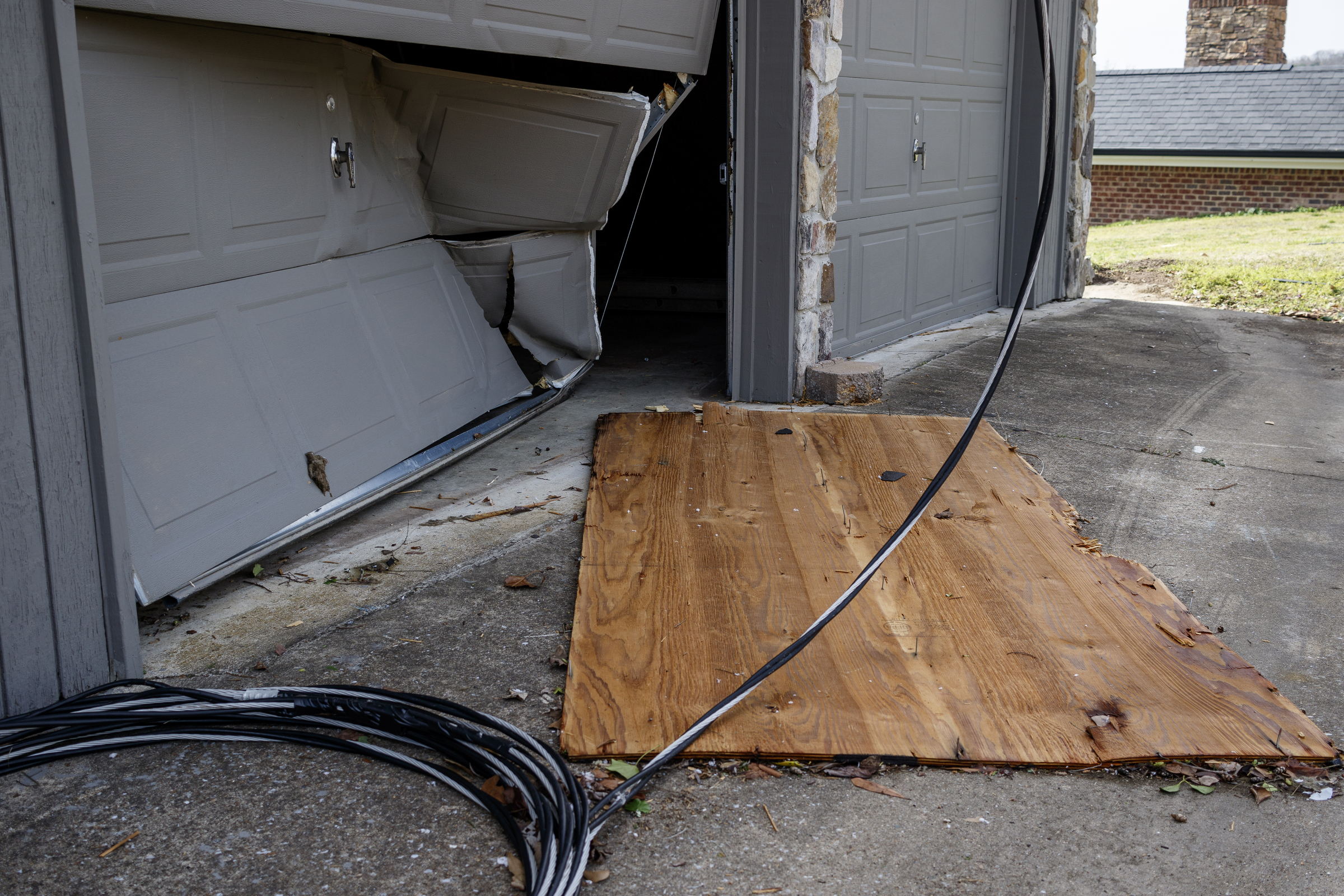 Bobby Keyes's garage door is dented where it was stuck by a board from a neighbor's home on Berkeley Lane on Wednesday, March 22, 2017, in Hixson, Tenn., after Tuesday evening storms caused isolated damage throughout the region.