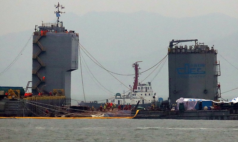 
              Workers prepare to lift the sunken Sewol ferry in waters off Jindo, South Korea, Thursday, March 23, 2017. South Korean workers on Thursday slowly pulled up a 6,800-ton ferry from the water, nearly three years after it capsized and sank into the violent seas off South Korea's southwestern coast, an emotional moment for a country that continues to search for closure to one of its deadliest disasters ever. (Lee Jin-wook/Yonhap via AP)
            