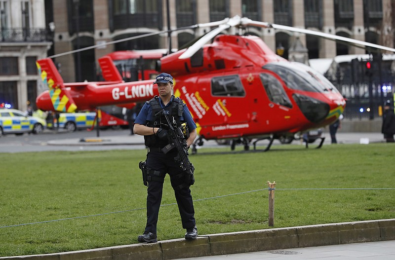 An armed police officer stands on Parliament Square outside of the Houses of Parliament in London, Wednesday, March 23, 2017 after the House of Commons sitting was suspended as witnesses reported sounds like gunfire outside.(AP Photo/Kirsty Wigglesworth)