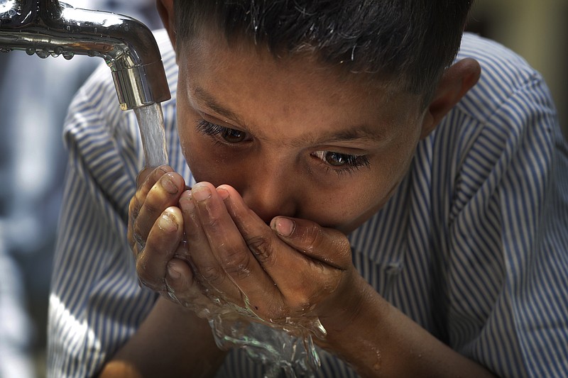 
              A boy drinks water from a newly set up water filtration tower in his school provided by Planet Water foundation, a non-governmental organization based in U.S. in Nai Basti Village, some 55 kilometers (35 miles) from in New Delhi, India, Wednesday, March 22, 2017. Schoolchildren cheered and village women clapped as a gush of clean water flowed through a set of gleaming steel taps connected to a newly installed water filtration plant in a dusty north Indian village on Wednesday. (AP Photo/Manish Swarup)
            