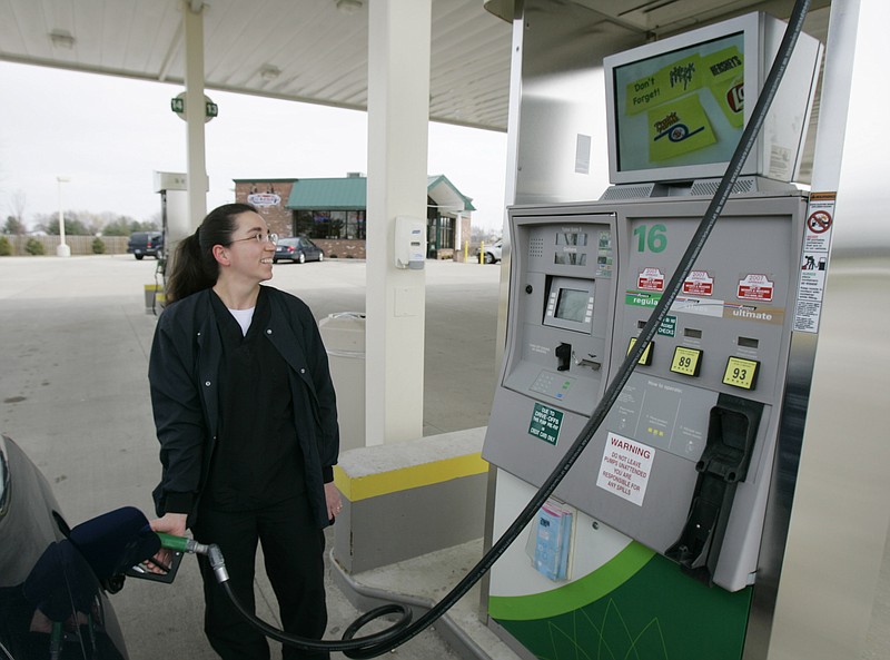 A woman fills her tank from a gas pump at a BP station in Anderson, Ind.