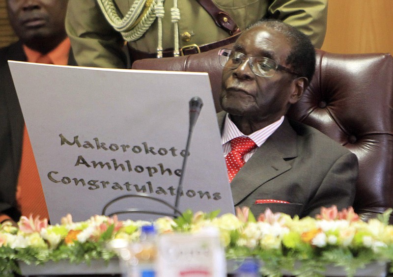 
              FILE -- In this Tuesday, Feb. 21, 2017 file photo, Zimbabwean president Robert Mugabe reads his birthday card as he marks his 93rd birthday at his offices in Harare. Mugabe might be slowing down but his busy foreign travel schedule has led the opposition to call him the "non-resident president." (AP Photo/Tsvangirayi Mukwazhi, File)
            