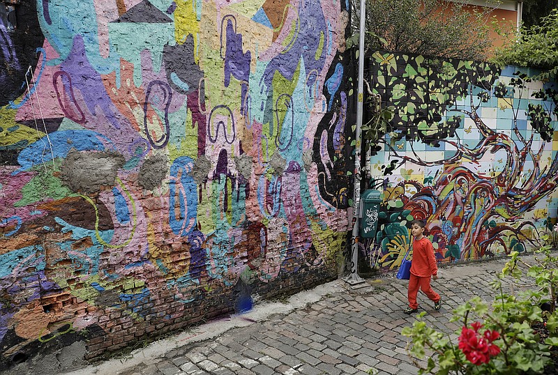 
              In this March 20, 2017 photo, a child walks alongside a street murals in Sao Paulo, Brazil. A campaign to clean up and beautify Sao Paulo has come under fire after the city's new mayor painted over a series of well-known graffiti murals. (AP Photo/Andre Penner)
            