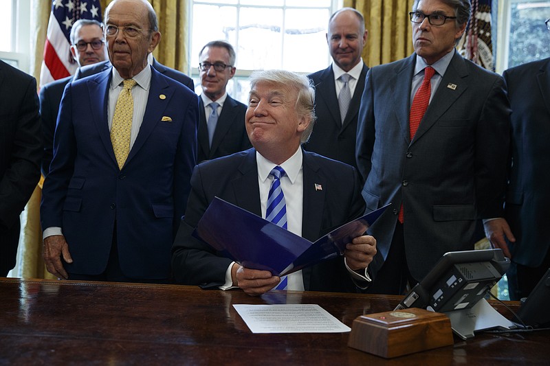 President Donald Trump, flanked by Commerce Secretary Wilbur Ross, left, and Energy Secretary Rick Perry, is seen in the Oval Office of the White House in Washington Friday, March 24, 2017, during the announcing of the approval of a permit to build the Keystone XL pipeline, clearing the way for the $8 billion project. (AP Photo/Evan Vucci)