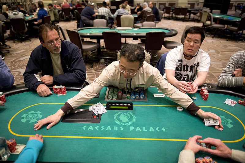 
              FILE - In this Feb. 27, 2013 file photo, dealer Han Kim, center, gathers up chips after a hand of Texas Hold 'em at a poker room in Caesar's Palace in Las Vegas.  Unlike the 2000s when casinos competed to lure fans of the game, poker's appeal has been weakening during this decade. Strip casinos had 405 tables and made $97 million in 2007. In contrast, the game only netted casinos $78 million last year after the number of tables decreased to 320.  (AP Photo/Julie Jacobson, File)
            