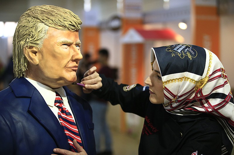 
              Turkish pastry chef Tuba Geckil adds the finishing touches to her figure of US President Donald Trump made out of cake icing which she created in two days, during a chocolate show in Istanbul, Saturday, March 25, 2017. (AP Photo/Lefteris Pitarakis)
            
