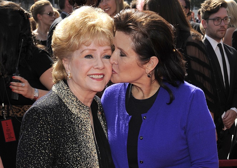 
              FILE - In this Sept. 10, 2011 file photo, Carrie Fisher kisses her mother, Debbie Reynolds, as they arrive at the Primetime Creative Arts Emmy Awards in Los Angeles. The mother-daughter actresses will be honored at a public memorial on Saturday, March 25, 2017, at the storied Hollywood Hills cemetery where both have been laid to rest. Fisher and Reynolds died one day apart in late December 2016. (AP Photo/Chris Pizzello, File)
            