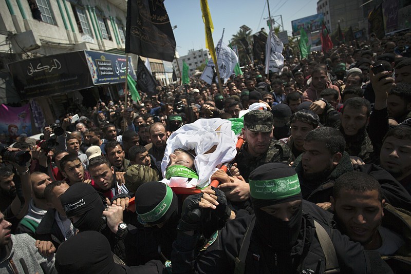 
              Masked gunmen from the Qassam brigade,  the militia wing of Hamas, carry the body of Mazen Faqha, during his funeral in Gaza City, Saturday, March, 25, 2017. The former Palestinian prisoner whom Israel sent to Gaza after his release was found shot dead at the entrance of his house in Gaza City. (AP Photo/ Khalil Hamra)
            