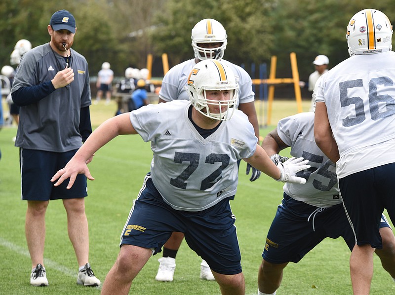 New UTC offensive line coach Nick Hennessey, left, watches as Josh Cardiello, center, goes through a drill at practice last week. Cardiello, who's preparing for his fifth and final college season, is the most experienced member of the Mocs' offensive line and is being looked to for leadership this spring.