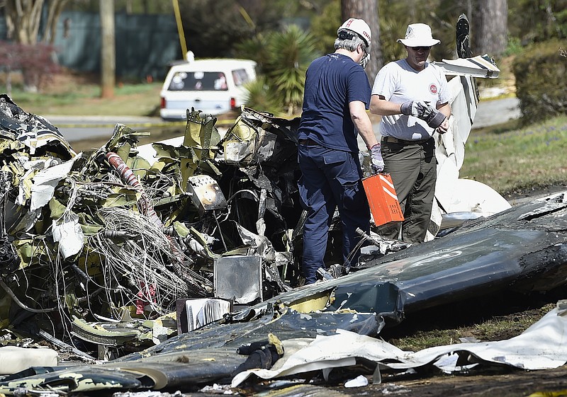 
              Officials with the National Transportation Safety Board and FAA remove a black box from a crashed Cessna Citation I, Saturday, March 25, 2017, in Kennesaw, Ga. The small plane crashed into a suburban Atlanta neighborhood Friday evening, killing the pilot and setting a house ablaze, officials said. The plane, on its way from Wilmington, Delaware, to Fulton County Airport, crashed next to a house and exploded, Cobb County Fire Department spokeswoman Denell Boyd told reporters. (AP Photo/Mike Stewart)
            