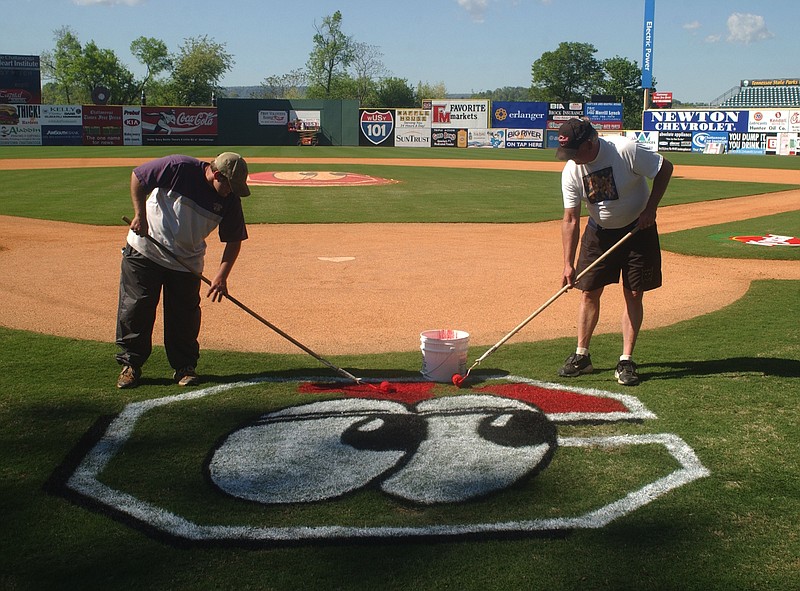 Bo Henley, left, and John Plumlee paint the Lookouts logo behind home plate Thursday afternoon in preparation for opening day. The Lookouts home opener is against West Tennessee Friday night. 