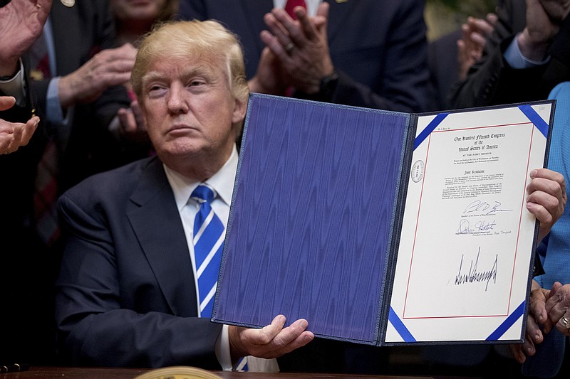 
              President Donald Trump holds up one of four bills during a signing ceremony in the Roosevelt Room of the White House in Washington, Monday, March 27, 2017. (AP Photo/Andrew Harnik)
            