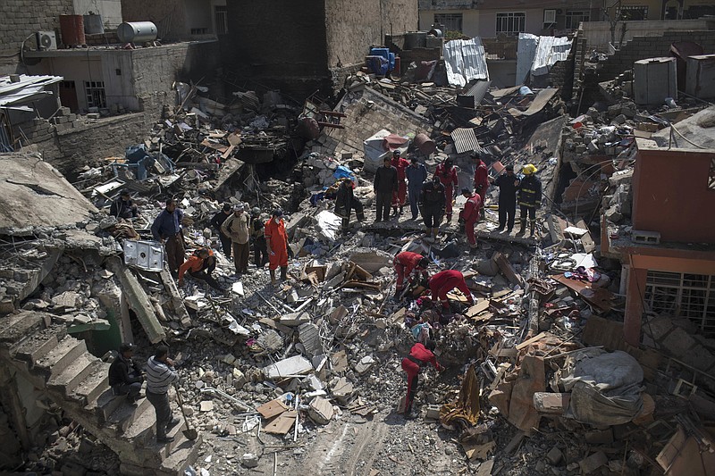 
              Civil protection rescue team work on the debris of a destroyed house to recover the body of people killed during fights between Iraq security forces and Islamic State on the western side of Mosul, Iraq, Friday, March 24, 2017. Residents of the Iraqi city's neighborhood known as Mosul Jidideh at the scene say that scores of residents are believed to have been killed by airstrikes that hit a cluster of homes in the area earlier this month (AP Photo/Felipe Dana)
            