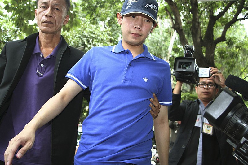 
              In this Sept. 3, 2012, photo, Vorayuth "Boss" Yoovidhya, center, whose grandfather co-founded energy drink company Red Bull, is escorted by police in Bangkok, Thailand. Vorayuth is accused of killing a Thai police officer in a hit-and-run in 2012, yet he still has not appeared to face charges. (Thai Daily News via AP)
            