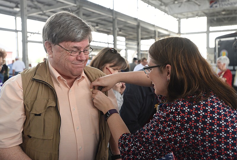 Mike Hillis is given a "Welcome Home" pin by Jessica Mines Dumitru during a commemoration for Vietnam veterans at the First Tennessee Pavilion Monday.