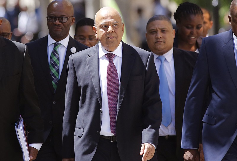 
              FILE -- In this Wednesday, Feb. 22, 2017 file photo South Africa's finance minister Pravin Gordhan, center, arrives at the South African Parliament to deliver the annual Budget speech in Cape Town, South Africa. Gordhan returned to Johannesburg on Tuesday, March 28, 2017, after being abruptly ordered to pull out of a trade promotion trip to the Britain and the United States, fuelling investor fears that he is about to be fired by President Jacob Zuma. (AP Photo/Schalk van Zuydam, File)
            