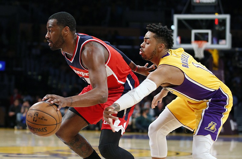 
              Washington Wizards guard John Wall, left, takes the ball past Los Angeles Lakers guard D'Angelo Russell, right, on the way to making a dunk during the first half of an NBA basketball game, Tuesday, March 28, 2017, in Los Angeles. (AP Photo/Danny Moloshok)
            