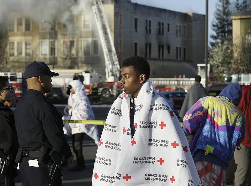 
              An evacuee waits as firefighters battle an early morning four alarm apartment fire Monday, March 27, 2017, in Oakland, Calif. (AP Photo/Ben Margot)
            