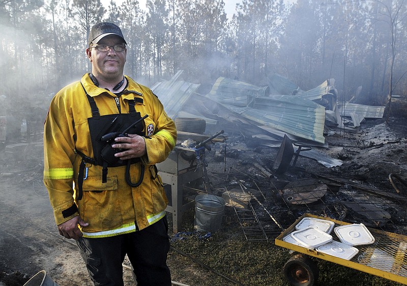 
              Nahunta volunteer firefighter Bill Bennett said the single wide mobile home behind him was the only occupied structure lost in a wildfire near Nahunta, Ga., Tuesday, March 28, 2017, that started when a permitted fire escaped containment. (Terry Dickson/Florida Times-Union via AP)
            